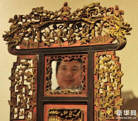 （2）2月9日，一位市民在觀看一個(gè)工藝繁復(fù)的帶鏡木雕盆架。