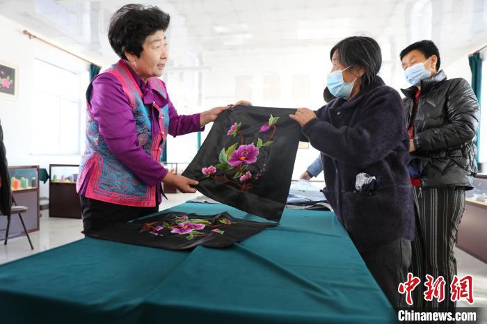 圖為白晶瑩驗(yàn)收繡工的作品。　科右中旗宣傳部供圖